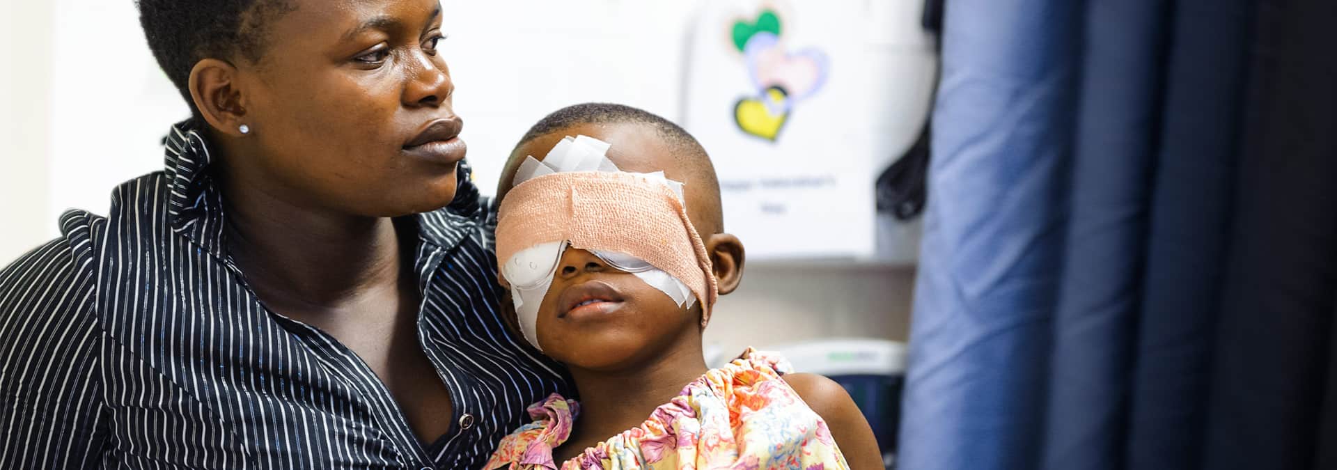 Junger Grauer Star Patient nach OP mit Augenbinde und Mutter