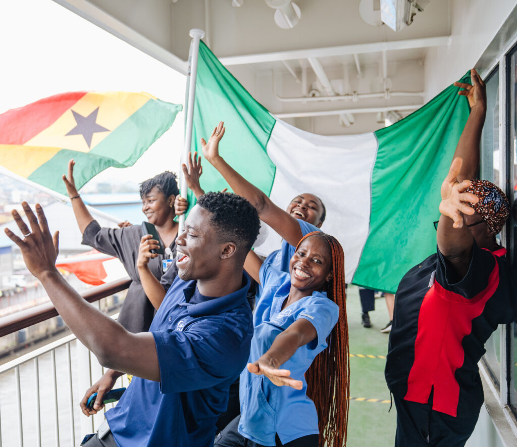 Crewmitglieder der Global Mercy winken zum Abschied der Hospitalschiffes vom Deck des Schiffes.